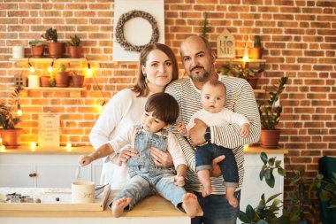 Genç ve güzel bir aile güneşli mutfakta eğleniyor ve yemek pişiriyor.