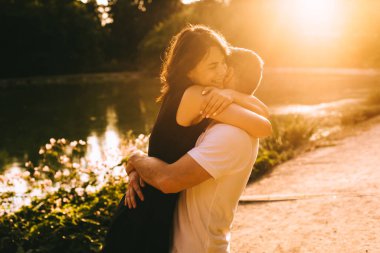 Yakışıklı genç baba ve güzel anne güneşli yaz doğasında sevimli küçük çocuklarıyla oynuyorlar.
