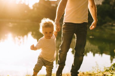 Yakışıklı genç baba ve güzel anne güneşli yaz doğasında sevimli küçük çocuklarıyla oynuyorlar.
