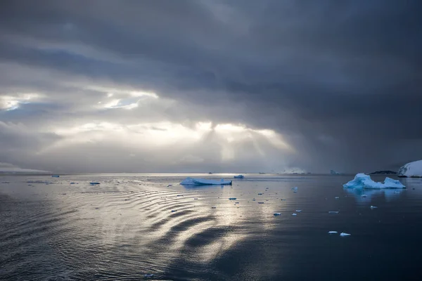 Raios de sol fogem thru nuvem, refletindo sobre a água com icebergs — Fotografia de Stock