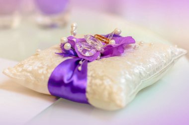 Mor ve beyaz küçük yastık üzerinde iki altın alyans