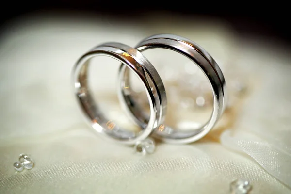 Dos anillos de boda dorados en un satén beige. Concepto de boda — Foto de Stock