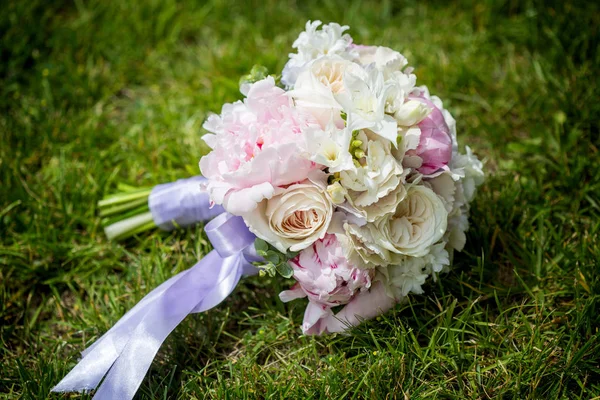 Buquê de casamento de flores roxas e brancas deitadas na grama — Fotografia de Stock