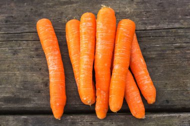 Tahta zemin üzerinde taze ve olgun havuçlar.