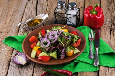 Sebzeli salata ve ahşap masada yeşiller.