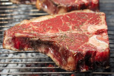 Portatif bir yaz barbeküsünde et ve sebze seçimi ön planda biberiye soslu sulu yağsız biftek üzerine odaklanmış..