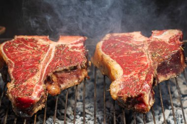 Portatif bir yaz barbeküsünde et ve sebze seçimi ön planda biberiye soslu sulu yağsız biftek üzerine odaklanmış..