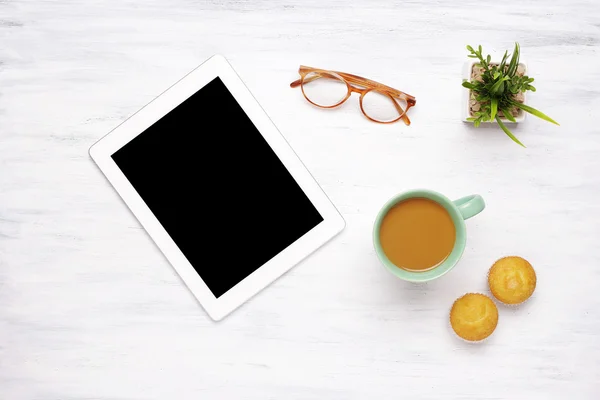 Tablet-Gerät, Tasse Kaffee und zwei Muffins auf einem Holztisch — Stockfoto