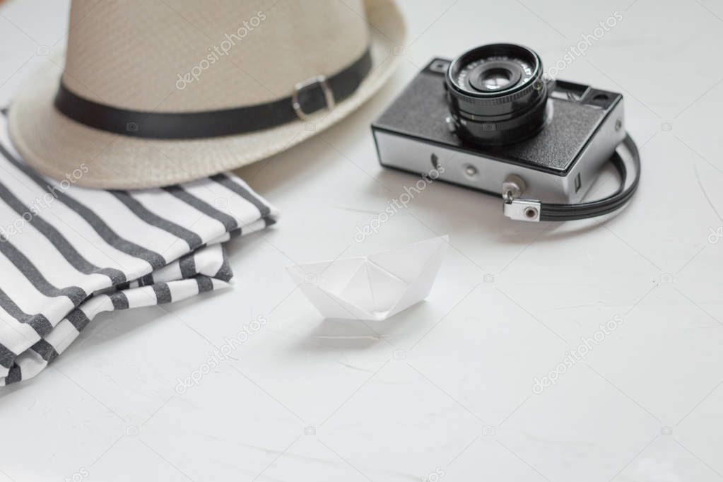 Flat lay of a straw hat, a photocamera and a stripped T-shirt. Vacation concept. Copy space.