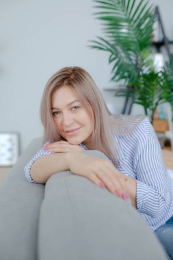 Sarışın kadın kanepede yatıyor.