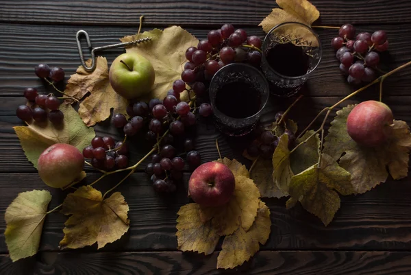 Два келихи з вином, яблуками та виноградом на дерев'яній поверхні — стокове фото