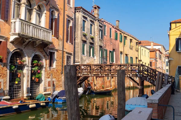 Venecia, Italia. Venecia, Italia. Barcos amarrados en estrecho canal bajo puente de madera — Foto de Stock