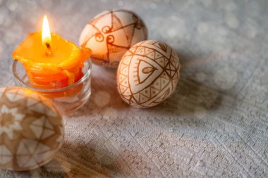 Geleneksel geometrik desenli Paskalya yumurtaları ve yanan bir mum.