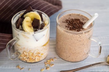 Malzemeler muz, çikolata, yulaf ezmesi, yoğurt ve smoothie ile iki cam bardak