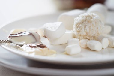 Beyaz şekerler, lokumlar ve arka planda fıstık ezmesi.