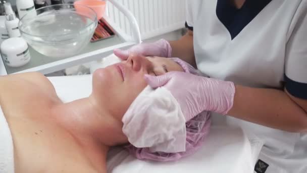 Beautician Reinigt Het Gezicht Van Een Volwassen Vrouw Met Natte — Stockvideo