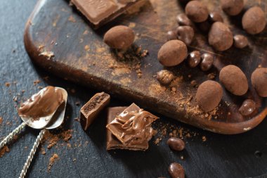 Various candies and chocolate with cocoa powder on a dark wooden surface