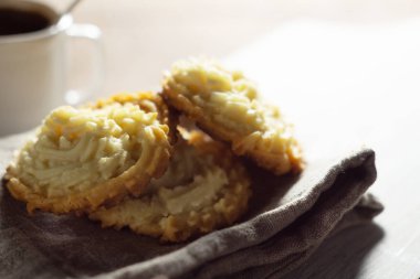 Keten peçete ve bir fincan kahvenin üzerinde kurabiyeler.