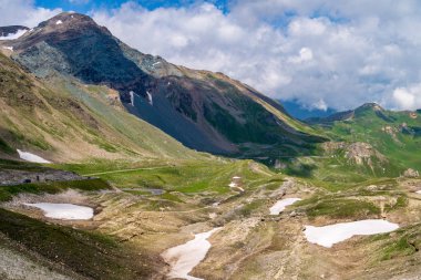 Grossglockner Lisesi boyunca kar yamaçları olan yeşil dağlar.