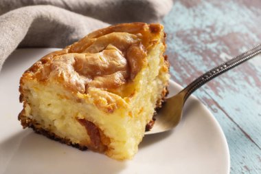 Ahşap bir masada beyaz tabakta süzme peynir güveci.