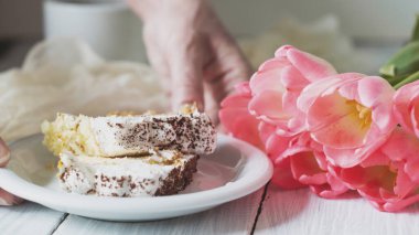 Masaya kadın eli koyun tatlı tiramisusu pembe lalelerin yanına.
