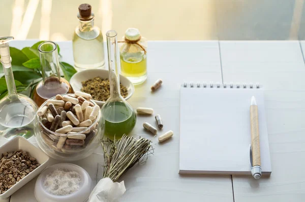 Diyet takviyeli çeşitli kapsüller, yaratımları için gerekli malzemeler ve kalemli bir defter. Kopyalama alanı