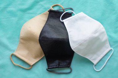 Yeşil kumaş üzerinde ev yapımı koruyucu, yeniden kullanılabilir antiviral maskeler.