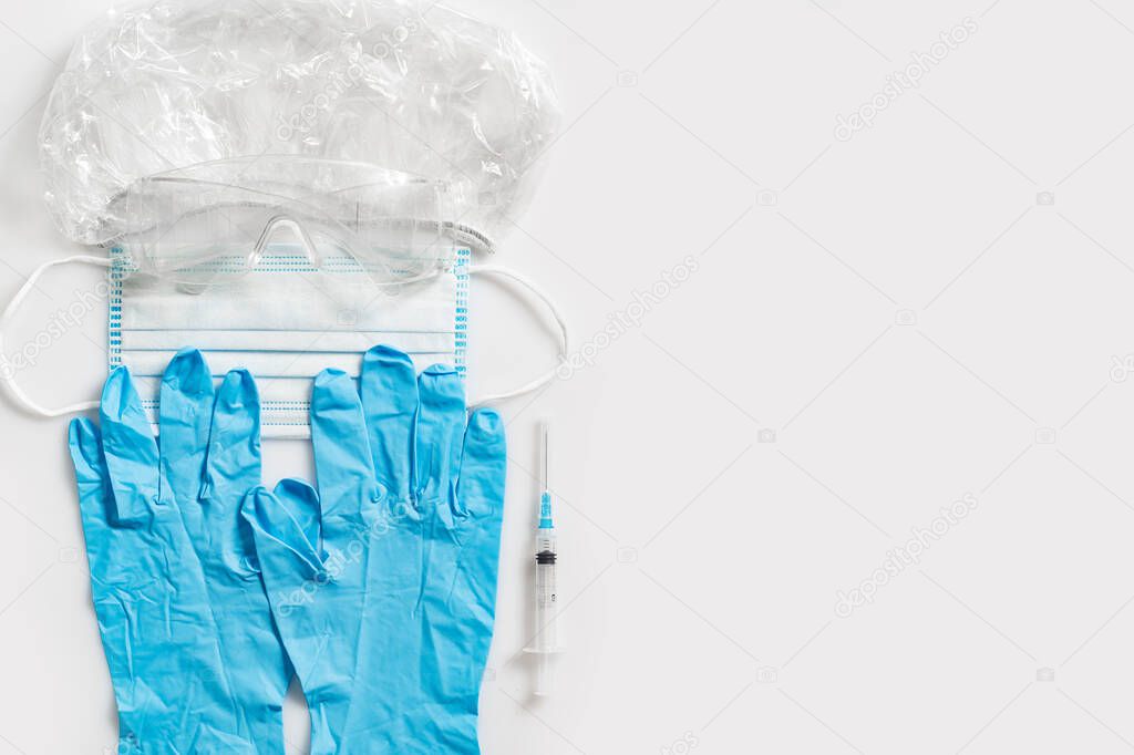 Covid-19 concept. Individual protection means, hat, goggles, gloves, antiviral mask and syringe with vaccine. Prevention and vaccinatio