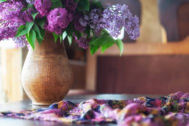 Sürahide bir demet leylak ve siyah ahşap bir masada ipek bir eşarp. Retro biçimi