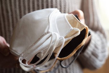 Kadının elinde ev yapımı koruyucu, yeniden kullanılabilir antiviral maskeler var.