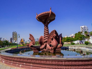 Phnom Penh, Kamboçya - 9 Ocak 2020: Arkasında Bağımsızlık Anıtı olan Preah Suramarit Bulvarı 'ndaki Naga Çeşmesi manzarası.