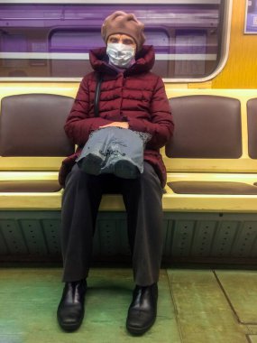 St. Petersburg, Rusya - 14 Nisan 2020: Büyükkadın metroda yalnız başına koruyucu maske takarak Covid-19 'un yayılmasına karşı.