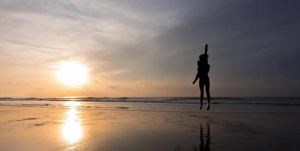 Boldog lány ugrás előtt a nap a strandon — Stock Fotó