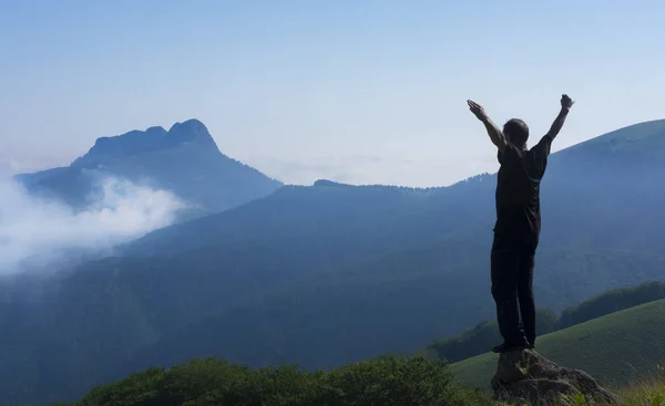 Hombre exitoso levantando brazos mientras caminaba por las montañas — Foto de Stock