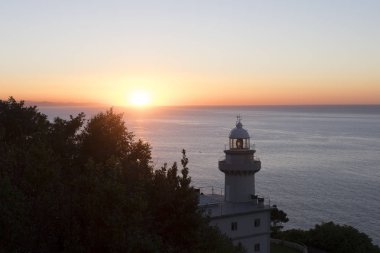 Lighthouse and sunset over the coast in San Sebastian clipart