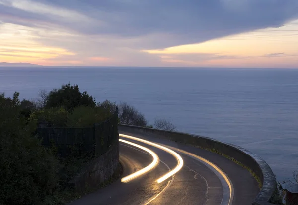 Car lights on the sea and road. Euskdi, Spain