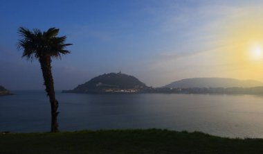 Palmiye ağacı gündoğumu, şehir San Sebastian, İspanya La Concha Körfezi içinde