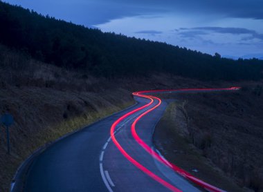 Car lights on mountain road at dusk, Jaizkibel, Basque Country, Spain clipart