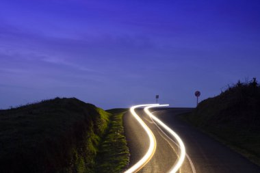 Gün batımında araba ışıkları dağ yolunda gökyüzünde Aiako Harriak Doğal Parkı, Euskadi