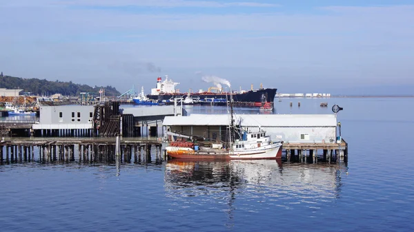 Port angeles, washington usa - Oktober 2014: Pier mit Fischerboot und riesigem Tankschiff — Stockfoto