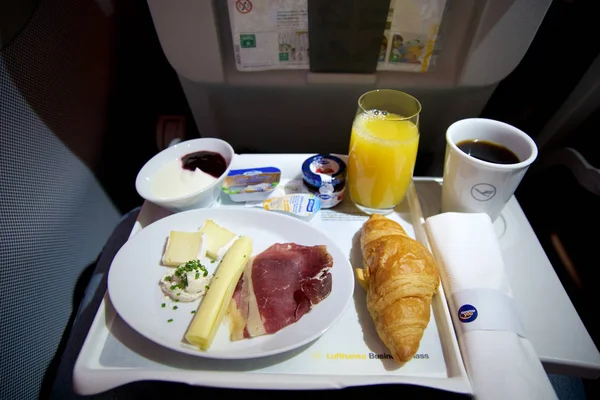 ФРАНКФУРТ, ГЕРМАНИЯ - 21 ЯН 2017: завтрак на самолете в бизнес-классе Lufthansa со свежим кофе, апельсиновым соком, сыром и беконом — стоковое фото