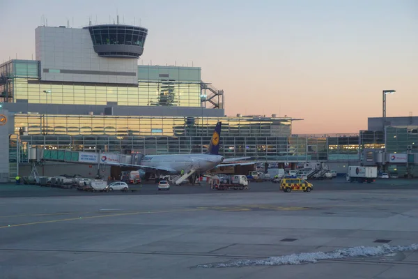 FRANKFURT, ALEMANIA - 20 DE ENERO DE 2017: Aeronaves, un Airbus de Lufthansa, en la puerta de la Terminal 1 del Aeropuerto Internacional de Frankfurt FRA durante la puesta del sol. Terminal 1 se completó en 1972 y casas —  Fotos de Stock
