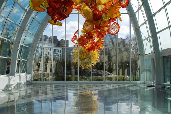 SEATTLE, WASHINGTON, USA - JAN 24th, 2017: Chihuly Garden and Glass museum featuring one of Dale Chihulys largest sculptures suspended from the ceiling of the glasshouse. City buildings are seen in — Stock Photo, Image