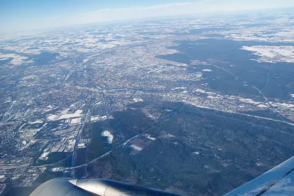 Frankfurt, Deutschland - 20. Januar 2017: Blick durch Flugzeugfenster auf Düsenflügel, Flügelblick über die verschneite Stadt Frankfurt am Main, Flughafen Fraport im Hintergrund — Stockfoto