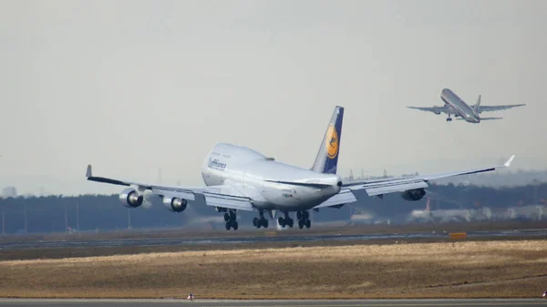 FRANKFURT, GERMANY - FEB 28th, 2015: The Lufthansa Boeing 747 - MSN 26427 - D-ABVN, named Dortmund landing at Frankfurt International Airport FRA and a starting plane in the background. The famous and — Stock Photo, Image