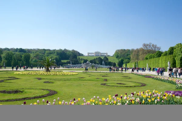 VIENNA, ÁUSTRIA - 30 de abril de 2017: Neptune Fountain Neptunbrunnen em grande parterre do parque público de Schoenbrunn com flores em primeiro plano e Gloriette na parte de trás, palácio de Schoenbrunn - antigo — Fotografia de Stock