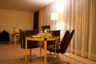 Vienna, Avusturya - 28 Nisan 2017: Romantik akşam bir şişe kırmızı şarap, tatlılar ve lüks otel odasında üç deri sandalye, Hilton çatı katı bir masada meyve ile