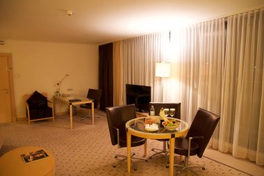 Vienna, Avusturya - 28 Nisan 2017: Romantik akşam bir şişe kırmızı şarap, tatlılar ve lüks otel odasında üç deri sandalye, Hilton çatı katı bir masada meyve ile