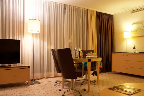 VIENNE, AUTRICHE - 28 avril 2017 : Soirée romantique avec bouteille de vin rouge, bonbons et fruits dans la chambre d'hôtel de luxe sur une table avec trois chaises en cuir, Hilton Penthouse Suite — Photo