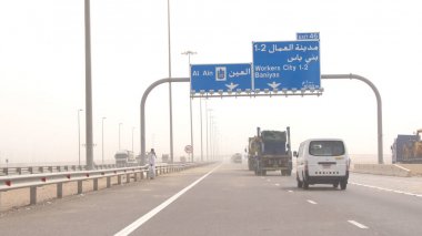 Abu Dhabi, Birleşik Arap Emirlikleri - 3 Nisan 2014: ısı pus ile Birleşik Arap Emirlikleri'daki ıssız bir otoyolda sürüş kamyonlar
